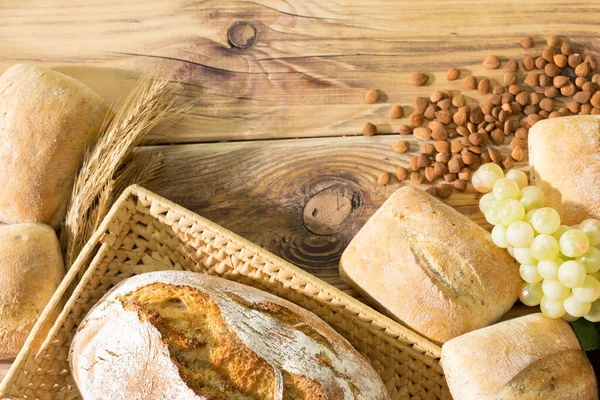 Shop decoration of the bakery with fresh bread, rolls and ears of ripe rye, and a bright bunch of grapes and bitter peach seeds. Bakery with taste. — Stock Photo, Image