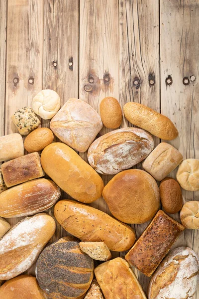 Many kinds and kinds of bread collected in one place on a wooden old shop counter as a decoration for a traditional bakery. View from above. — Stock Photo, Image