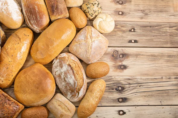 Many kinds and kinds of bread collected in one place on a wooden old shop counter as a decoration for a traditional bakery. View from above. — Stock Photo, Image