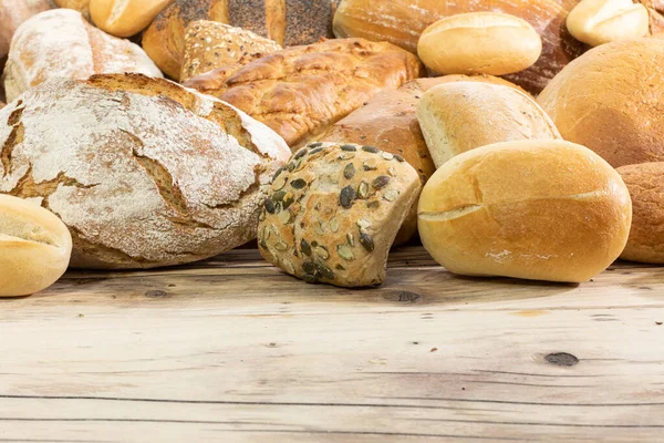 Many kinds and kinds of bread collected in one place on a wooden old shop counter as a decoration for a traditional bakery. View from above. — Stock Photo, Image