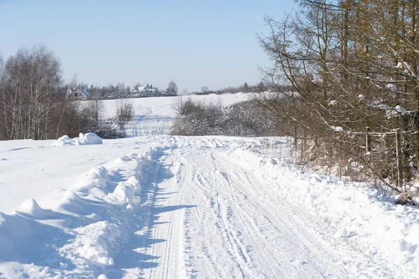 Venkovská prašná cesta plná sněhu v zimě. Můžete vidět stopy aut a silnice po odstranění sněhu. — Stock fotografie