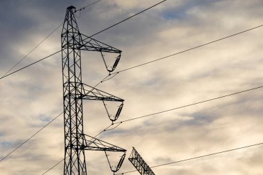 Güç direği yavaşça batan güneşe karşı. Yüksek voltaj güç hatları.