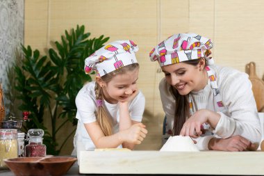 Annesi kızına unun elek yoluyla ellendikten sonra ne kadar hassas olduğunu gösterir. Aile çevresinde un ile mutfak deneyimleri.