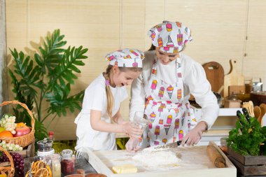 Pizza hamuru hazırlarken, beş çocuk annesi ve kızı buğday ununa sıcak su döker. Anne ve çocuğun mutfak hazırlıklarında ortak çalışmaları.