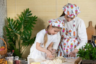 Pizza hamuru hazırlarken, beş çocuk annesi ve kızı buğday ununa sıcak su döker. Anne ve çocuğun mutfak hazırlıklarında ortak çalışmaları.