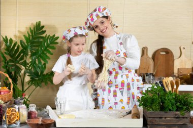 Hazır pizza hamurunu durana kadar elinde tutarsın. Beş yaşında bir kızı olan bir anne. Anne ve bebek mutfakta hamuru birlikte yapıyorlar..