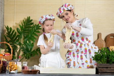 Hazır pizza hamurunu durana kadar elinde tutarsın. Beş yaşında bir kızı olan bir anne. Anne ve bebek mutfakta hamuru birlikte yapıyorlar..