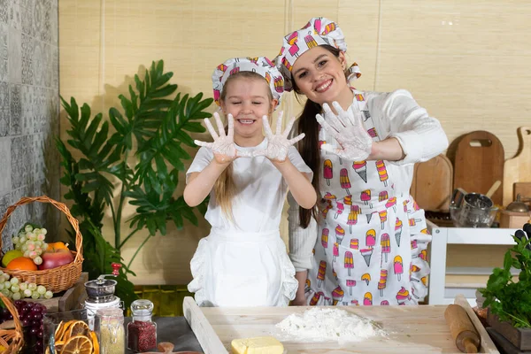 Anne ve kızı oynadıkları buğday unuyla birlikte ellerini kameraya gösteriyor. Mutfakta beyaz unla çok eğleniyoruz..