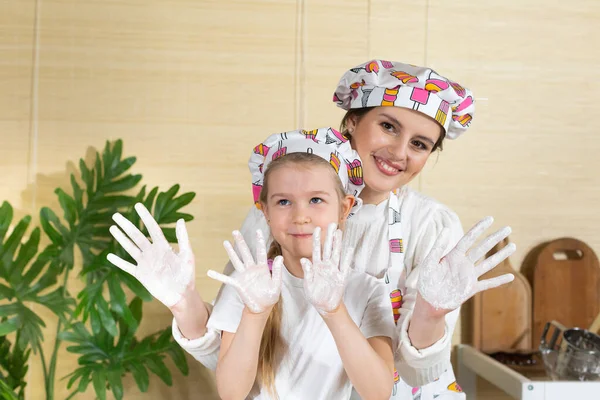 Anne ve kızı oynadıkları buğday unuyla birlikte ellerini kameraya gösteriyor. Mutfakta beyaz unla çok eğleniyoruz..