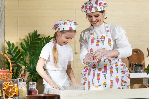 Tavuk öküzünü kırıp hamurun üstündeki yığın halinde duran ellenmiş ve tuzlanmış una eklemek. Anne ve çocuğun mutfak hazırlıklarında ortak çalışmaları.