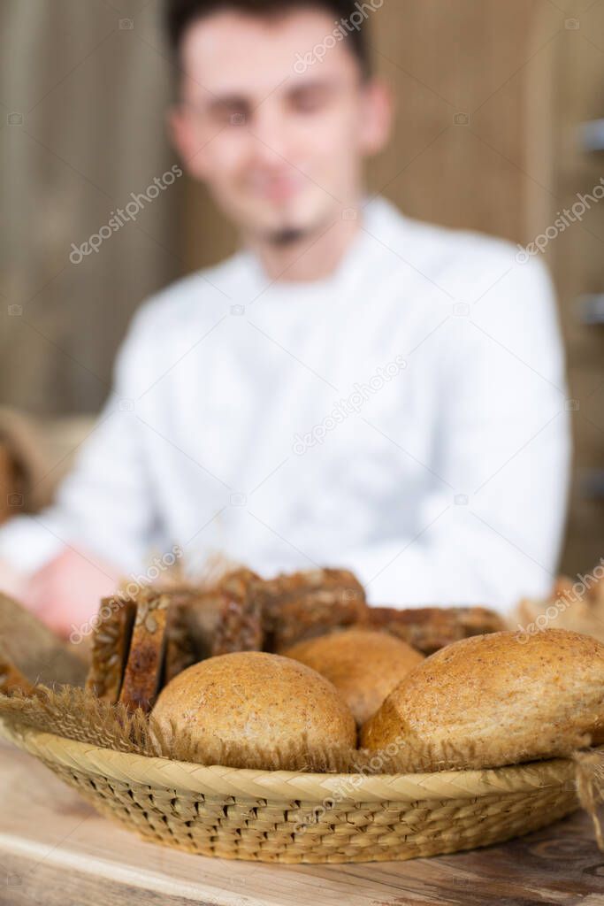 A handsome baker serves fresh bread to thirsty customers. Sale of bread in a traditional bakery store.