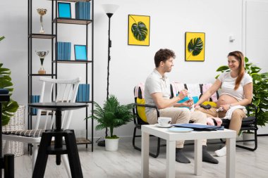 Evli bir çift, doğmamış çocukları için kıyafet seçer. Gelişmiş hamilelik. Tercih edilebilir bir yeri olan modern tarzda parlak bir oturma odası..