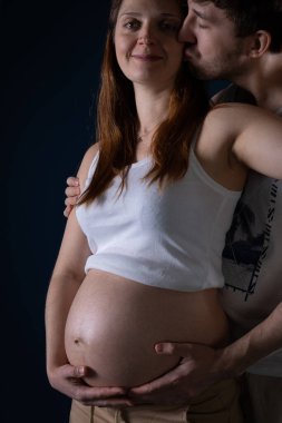 Aşık bir koca hamile olan karısını öper. Ellerini karnına koy. Hamileliğin dokuzuncu ayı. Kutsanmış durum.