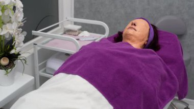 Müşteri kozmetik bir yatakta, yüzünde alg maskesiyle uzanıyor ve derin derin nefes alıyor. İyice kurumasını bekle.