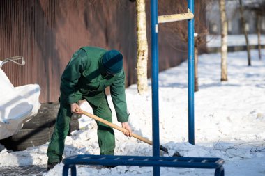 Bir el işçisi kürekle ıslak kar ve buz topluyor.