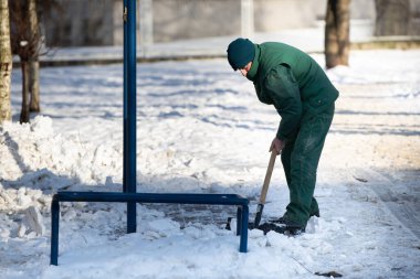 Bir el işçisi kürekle ıslak kar ve buz topluyor.
