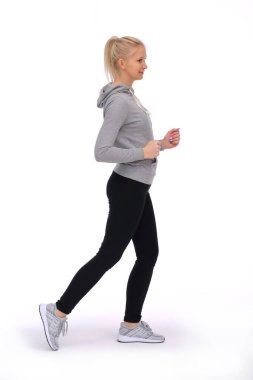 Genç bir kız beyaz bir arka planda koşuyor.