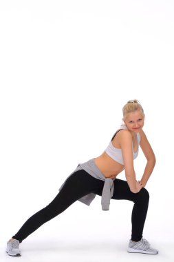 Genç bir kız bacak kaslarını çalıştırır ve gerer. Eller dizde dinleniyor.