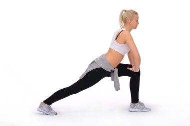 Genç bir kız bacak kaslarını çalıştırır ve gerer. Eller dizde dinleniyor.