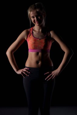 Kadın göbeği mükemmel bir şekilde kaslı ve eğitimli ve tüm set siyah bir arka planda ve eller kalçanın üzerinde duruyor.