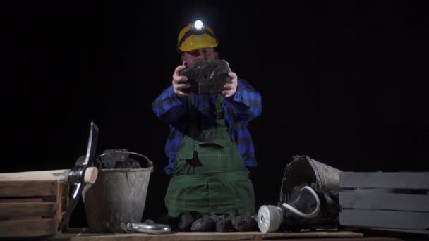 Un mineur tourne un gros morceau de charbon noir dans ses mains — Video