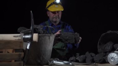 Bir madenci elinde koca bir kömür yığınını çevirir.