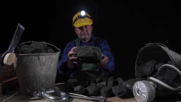 A miner turns a large lump of black coal in his hands — Stock Video