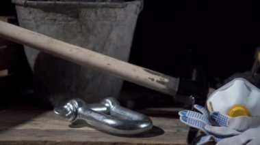 Ahşap platformda içinde kömür olan bir kova, filtresi olan koruyucu bir maske ve parlayan bir el feneri olan bir miğfer görebilirsiniz.