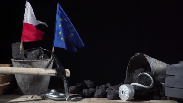 Un drapeau polonais et un drapeau de l'Union européenne sont placés dans un seau de charbon noir et tous deux flottent dans le vent — Video