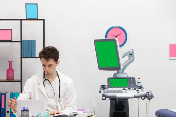 Un joven médico de atención primaria revisa la orden de cita de sus pacientes para hoy en su computadora portátil. Pantalla verde —  Fotos de Stock