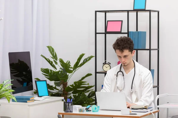 Un médico de atención primaria joven ingresa los datos del paciente en una base de datos portátil. Oficina de médicos —  Fotos de Stock