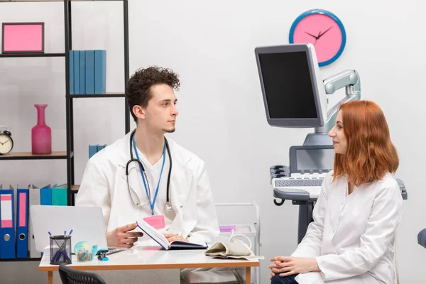 Un médico habla con una enfermera en su consultorio mientras espera al siguiente paciente. Médico de atención primaria —  Fotos de Stock