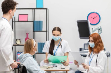 Ziyaretten önce, doktor salgın hastalıklar için hastaların tıbbi geçmişini dikkatle kontrol ediyor. Doktorun ofisinde tekerlekli sandalyede oturan 50 yaşında bir kadın..