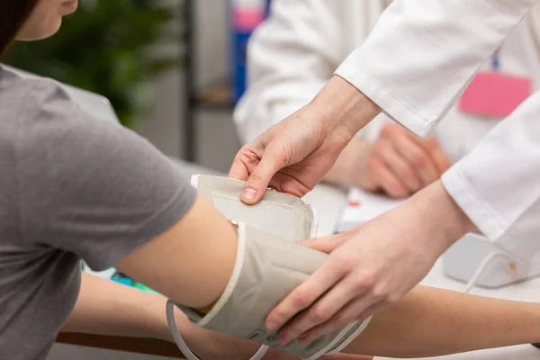 Close-up van een verpleegster die een bloeddrukmeter op een patiëntenarm plaatst. Huisarts. Bureau voor artsen — Stockfoto