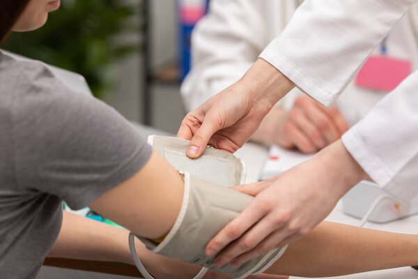 Крупным планом медсестра помещает монитор артериального давления на руку пациента. Врач общей практики. Кабинет врача