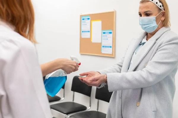 Devam eden bir salgın karşısında tıbbi personel tarafından kliniğe giren hastaların el dezenfeksiyonu — Stok fotoğraf