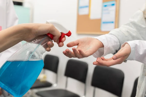 Vista de cerca de las manos desinfectadas de los pacientes que ingresan a una clínica, realizada por el personal médico frente a una pandemia — Foto de Stock