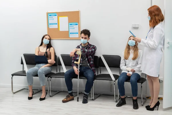 The doctor reads out the next person in line. During a pandemic everyone must wear protective masks