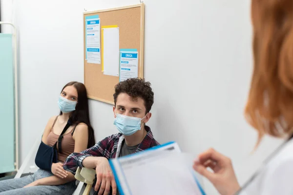 Лікар читає наступну людину в черзі. Під час пандемії кожен повинен носити захисні маски. Крупним планом постріл — стокове фото