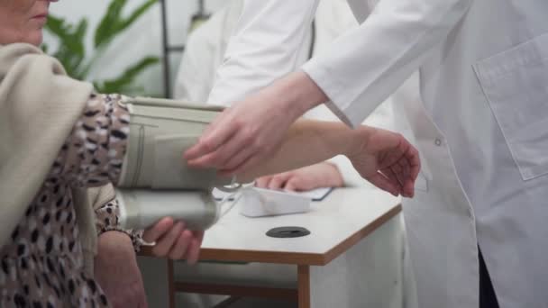 Une infirmière place un tensiomètre sur le bras d'un patient pour effectuer un contrôle de routine. Bureau des médecins — Video