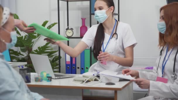 Pacient přijel na invalidním vozíku z úrazového oddělení do ordinace pro doktory na rutinní prohlídku. Ochranná maska zakrývající její ústa a nos. — Stock video