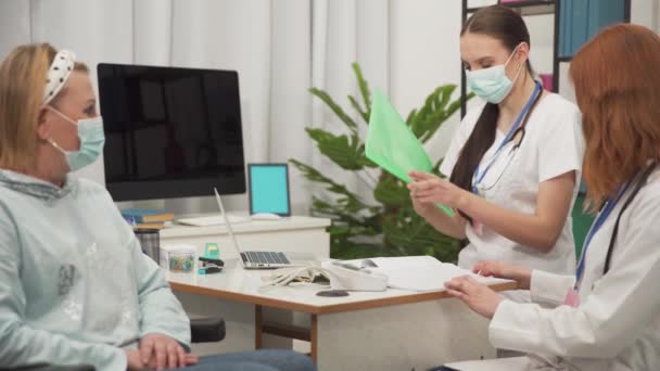 医療従事者は定期点検のために車椅子に50歳の女性を輸入しています。口と鼻を覆うマスク保護. — ストック動画