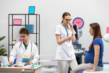 Bir doktor hamile bir hastayı muayene etmeye hazırlanır. Doktor önceki ziyaretin sonuçlarını kontrol ediyor..