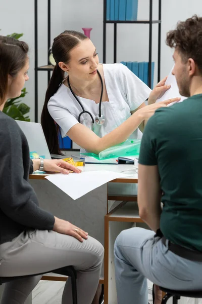 Um ginecologista está explicando os resultados dos testes para uma paciente grávida. Um casal no escritório de ginecologistas. — Fotografia de Stock