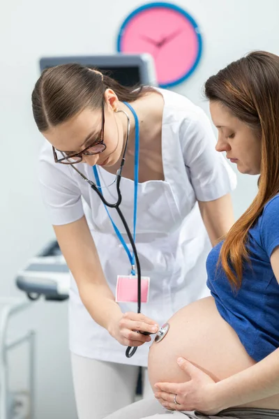 El médico escucha el abdomen de una paciente embarazada con un estetoscopio. Oficina médica profesional — Foto de Stock