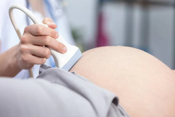 Visão de perto do transdutor de ultra-som no abdômen de uma mulher grávida. Escritório de ginecologia. — Fotografia de Stock