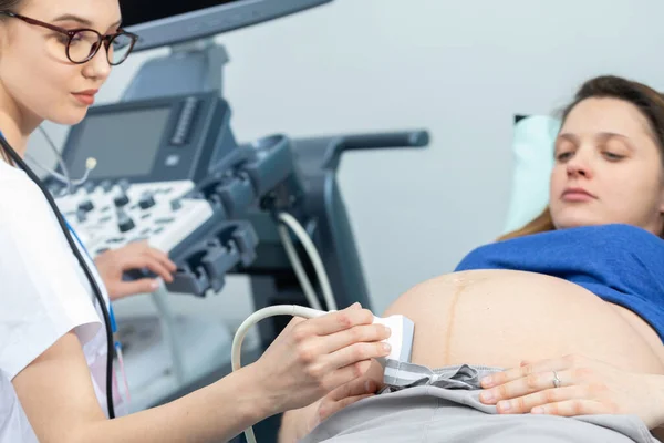 En la sala de ginecología, una doctora examina a una mujer embarazada usando una máquina de ultrasonido. — Foto de Stock