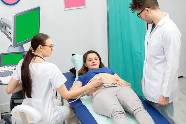 Una enfermera realiza un ultrasonido a una paciente embarazada bajo la guía del médico que la atiende. Pantalla verde. — Foto de Stock