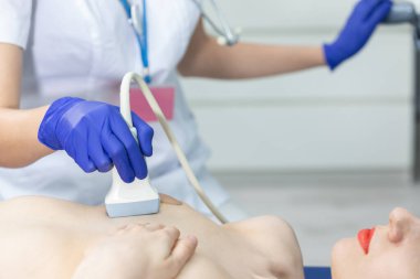 Ultrason kullanan bir bayan doktor genç bir hastanın göğüslerini muayene ediyor. Doktorun ofisi..