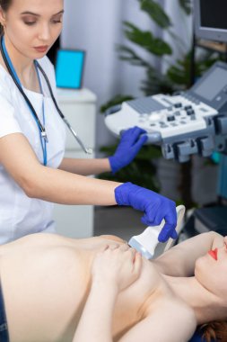 Genç bir doktor hastaları ultrasonla muayene eder. Göğüs kanserinin başlamasını önlüyor. Doktorun ofisi..
